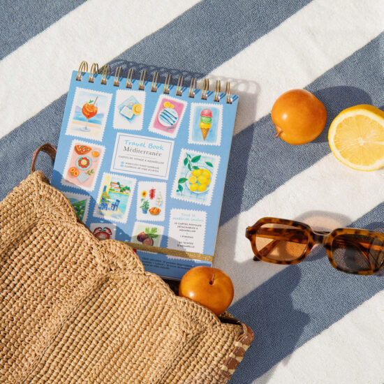 חוברת Travel Book Mediterranean על מגבת עם תפוזים ומשקפי שמש